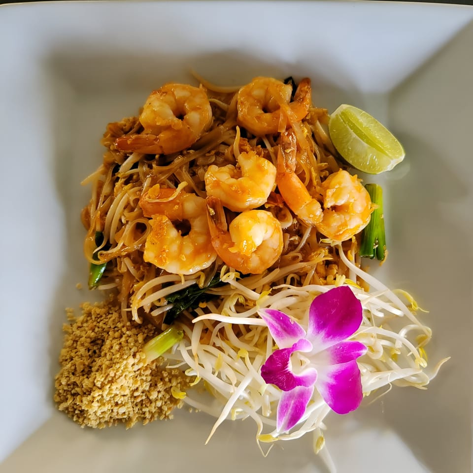 Lan Xang's shrimp Pad Thai with noodles, bean sprouts, crushed peanuts, lime, and an orchid.